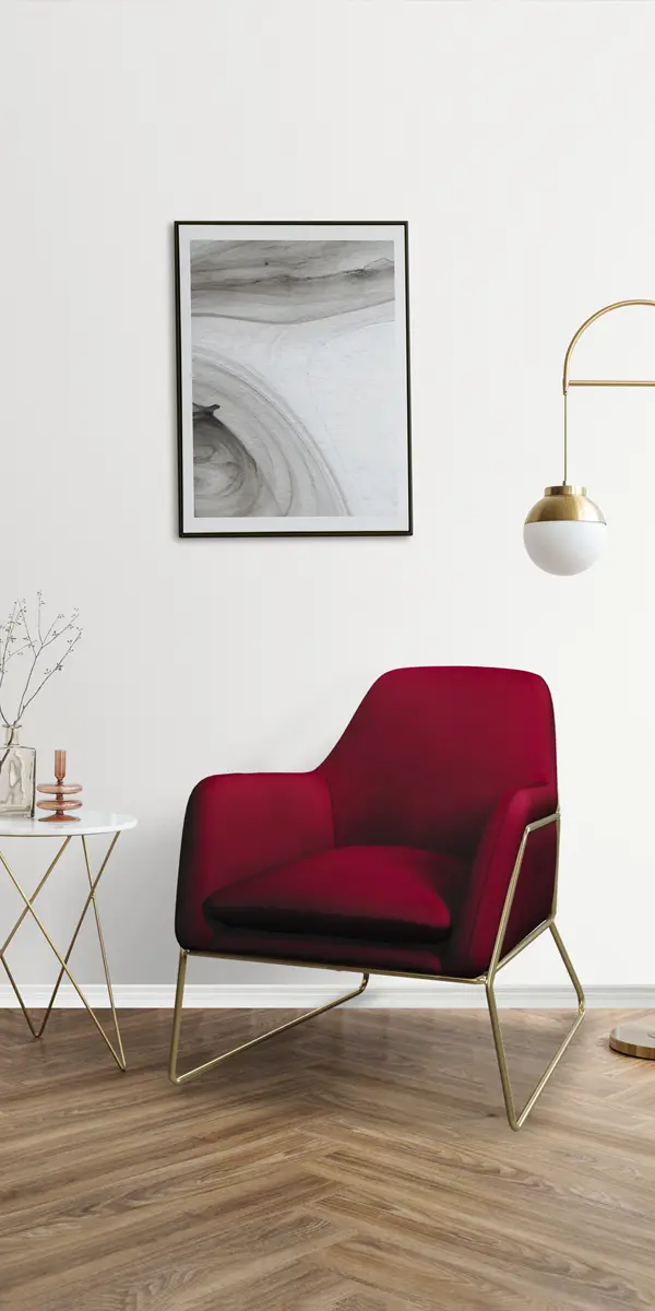 Modern minimalist living space with a stylish red armchair, a small side table with a decorative vase, sleek floor lamp, and framed abstract wall art